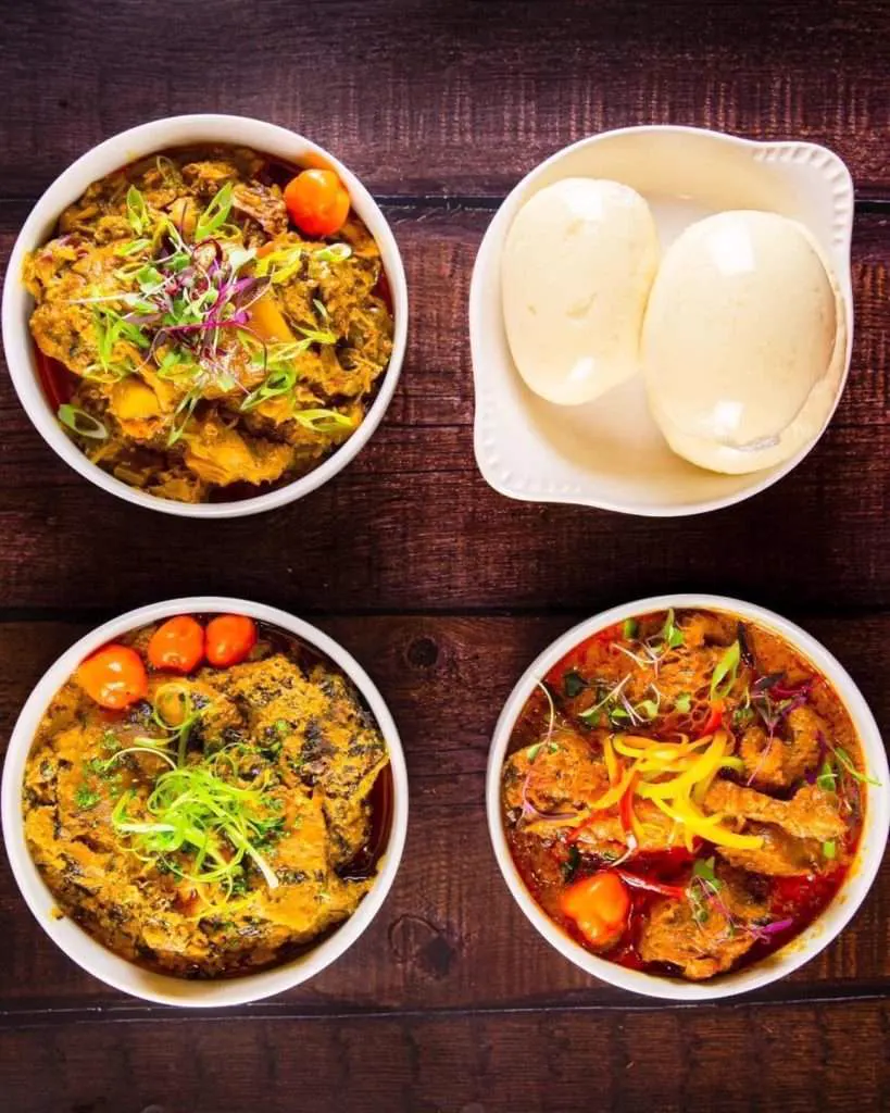 Three bowls of West African stew beside a dish of fufu